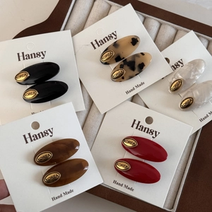 Detail showing five colors of acetate hair clips on a card with gold metal labels