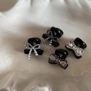 Detail of four black bow hair clips with pearls and rhinestones on beige ceramic plate