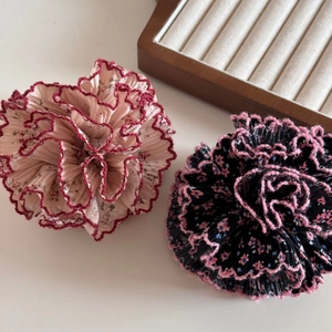 Gros plan de pinces à cheveux fleurs en tissu plissé floral avec détails volantés