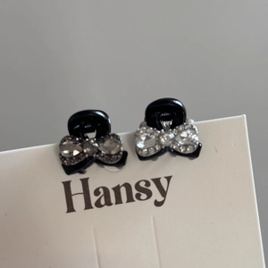 Detail of mini black hair claws with elegant rhinestone bow designs on white card
