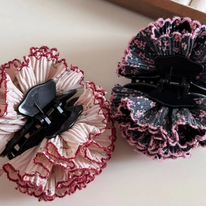 Détail de pinces à cheveux en tissu plissé à fleurs avec pétales élégants et base noire