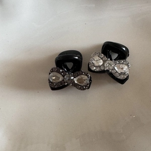 Detail of elegant black bow hair clips with sparkling rhinestones and pearl accents