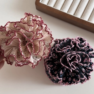 Détail de chouchous plissés à fleurs avec bords ondulés en tissu beige et noir