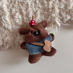 Detail of cute teddy bear plush charm with mushroom hat and blue denim vest