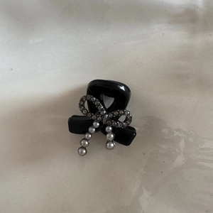 Detail of mini black hair claw clip featuring rhinestone bow and pearl tassels charm
