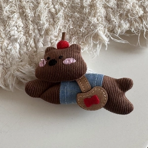 Detailed close-up of a cute brown bear plush accessory with denim clothing and cherry decor