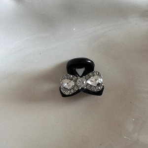 Detail view of mini black hair claw clip featuring a sparkling rhinestone bow decoration