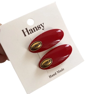 Pair of elegant red oval acetate hair clips with vintage gold metal accents on display card