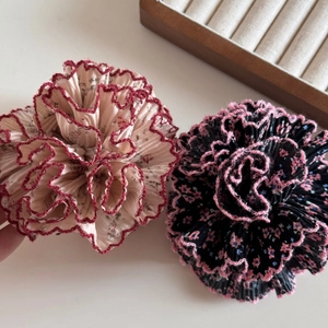 Gros plan de deux chouchous en tissu floral avec texture plissée et bords cousus délicats