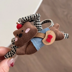Detailed view of a cute brown corduroy bear hair accessory with denim and leather accents