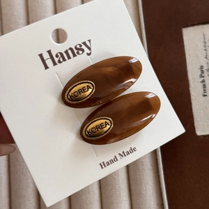 Detail of tortoise shell acetate hair clips with gold metal tag and marble texture