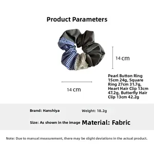 Detail view of large grey fabric hair scrunchie with blue plaid pattern and lace trim