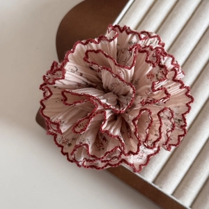 Détail d'un chouchou en tissu floral avec imprimé rose vintage et bords ondulés rouges