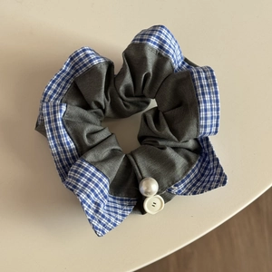 Detail of grey scrunchie with blue plaid trim featuring pearl and button accents