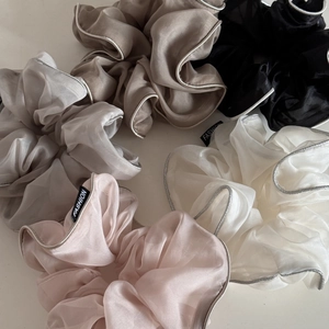 Detail of organza scrunchies with silver trim edges and fashion logo tags in five colors