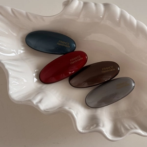 Set of four minimalist oval hair clips in navy, red, brown, and grey with glossy finish