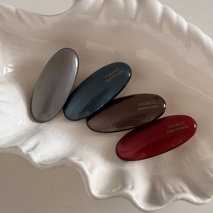 Detail of four oval hair clips in vintage colors on a white shell-shaped tray