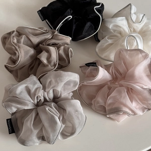 Flat lay of five sheer organza scrunchies in pastel tones with silver edge and fashion tag