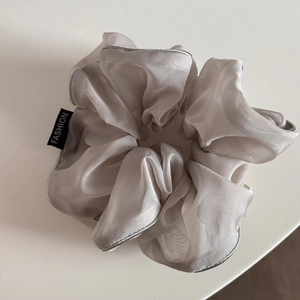 Detail of silver-grey organza scrunchie featuring elegant silver edging and fashion label