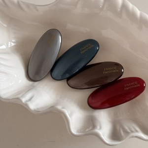 Close-up of small oval hair clips in dark colors with France Handmade gold lettering