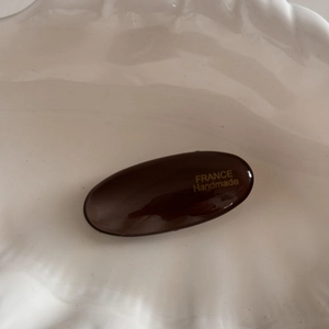 Detailed view of dark brown oval hair clip with gold France Handmade lettering