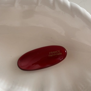 Detailed close-up of a red oval resin hair clip with gold France Handmade lettering