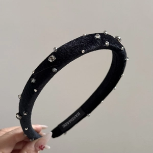 Close-up of black velvet headband with silver rivets and shiny rhinestones detail