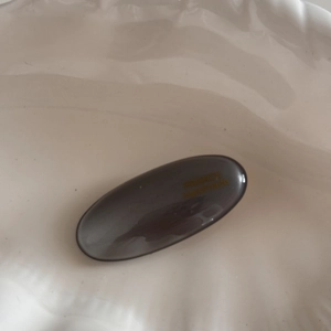 Detail of grey resin oval hair clip with gold France Handmade lettering on white ceramic