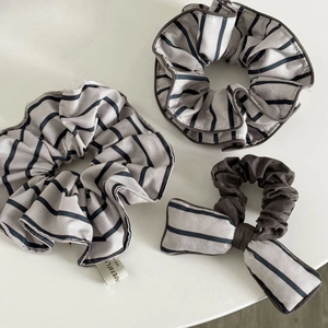 Detail of grey striped scrunchie set with brown piping and soft fabric texture