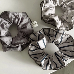 Detailed view of three vintage-style scrunchies with floral and striped fabric patterns