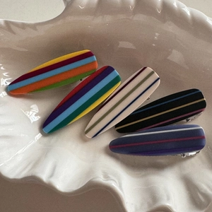 Five pieces of rainbow striped matte duckbill hair clips arranged in a white shell tray