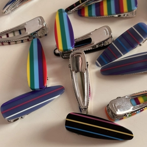 Close-up of rainbow striped teardrop hair clips with polished silver metal duckbill base