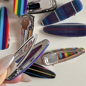Close-up of colorful striped hair clips with metal base showing the opening mechanism