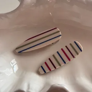 Close-up of rainbow striped acetate hair clip in a white decorative shell tray