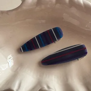 Detail of blue striped resin hair clip with smooth finish on a beige tray