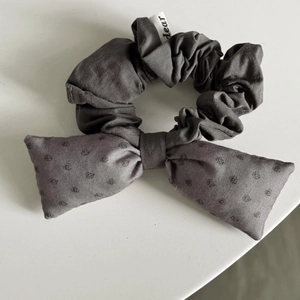 Detail of dark grey hair scrunchie with bow tie and tiny dear tag on white background