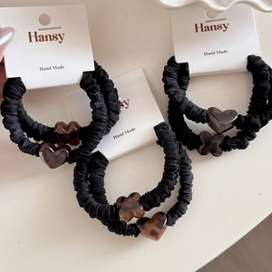 Detailed view of black elastic hair scrunchies with leopard print heart and flower charms