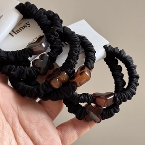 Set of black elastic scrunchies with amber tortoise shell charms on a display card