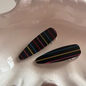 Macro detail of rainbow striped hair clips set on a decorative white wave tray