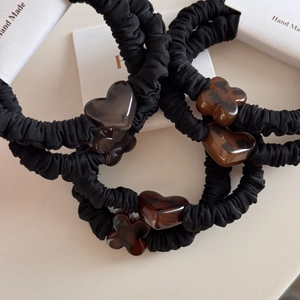 Close-up of black scrunchies with heart and clover leopard print resin charms