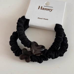 Set of two black scrunchies with shiny heart and flower charms on a display card