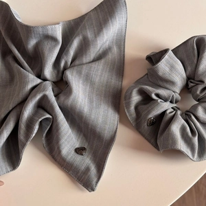 Macro detail of gray striped fabric scrunchie with heart-shaped metal pendant
