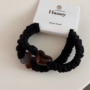 Detail of two black scrunchies with heart and flower amber acrylic charms in a set