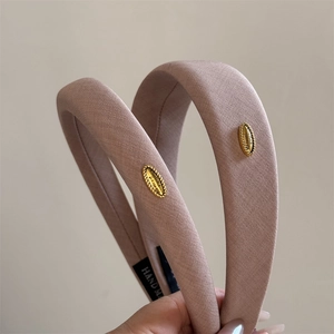 Detailed view of handmade mauve fabric headbands with gold metallic logo plate