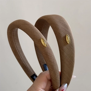 Close-up of deep brown fabric headband featuring a vintage oval gold metal buckle detail