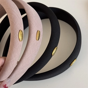 Detail showing the refined gold metal label and twill fabric texture of wide sponge headbands