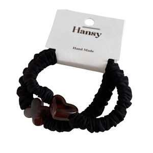 Set of two black scrunchies with acrylic heart and cross charms on a white brand card