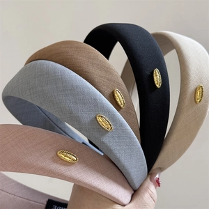 Close-up of five colorful fabric headbands with elegant golden metal logo plates