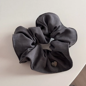 Detail of grey twill fabric hair scrunchie with a small silver heart-shaped metal charm