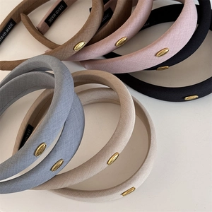 Detail of wide padded fabric headbands with gold logo and various elegant colors